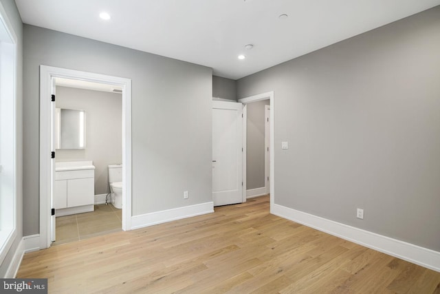 unfurnished bedroom with ensuite bath and light wood-type flooring