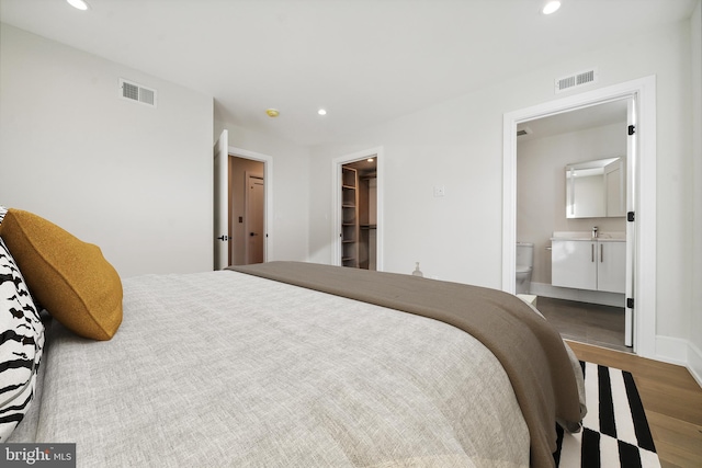 bedroom featuring a closet, dark hardwood / wood-style flooring, sink, ensuite bath, and a spacious closet