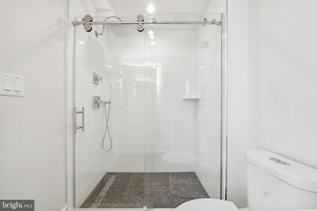 bathroom featuring toilet and a shower with door