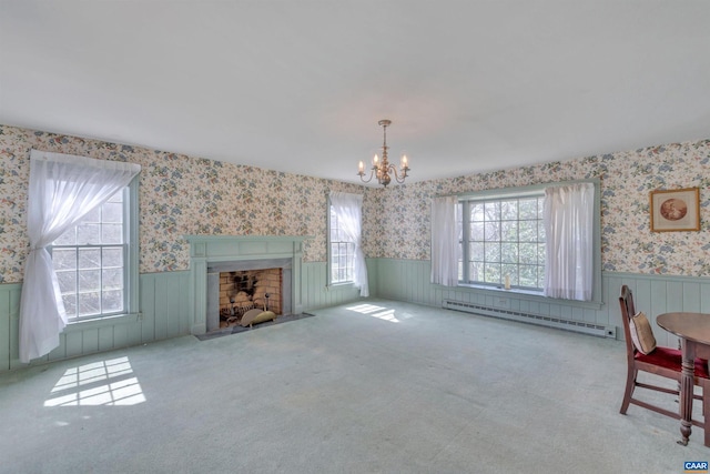 living room featuring a notable chandelier, baseboard heating, light carpet, and a healthy amount of sunlight