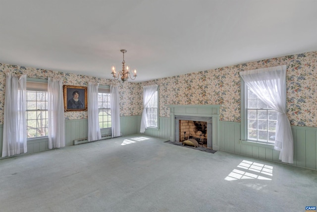 unfurnished living room featuring a healthy amount of sunlight, light colored carpet, and a notable chandelier