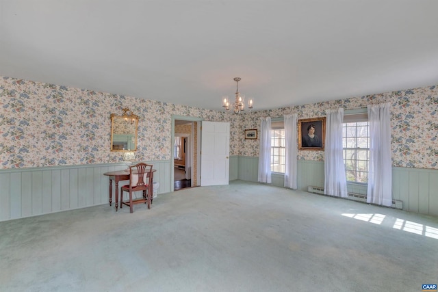 spare room featuring a chandelier, a baseboard radiator, and light carpet