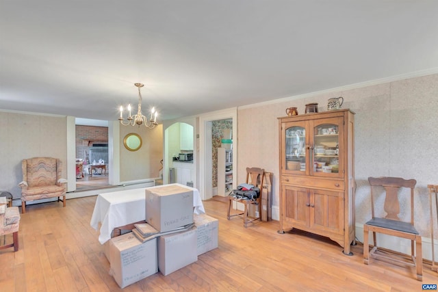 dining area with crown molding, light hardwood / wood-style flooring, and an inviting chandelier