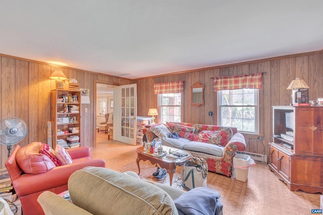 living room featuring light tile floors, wood walls, baseboard heating, and french doors