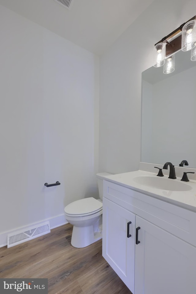 bathroom with toilet, hardwood / wood-style floors, and vanity