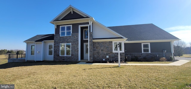 view of front of property featuring stone siding, central AC, and a front lawn