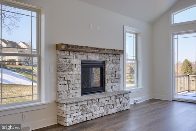 unfurnished living room with plenty of natural light and a stone fireplace