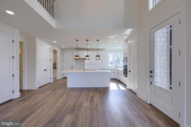 kitchen featuring hanging light fixtures, white cabinets, dark hardwood / wood-style floors, and a kitchen island