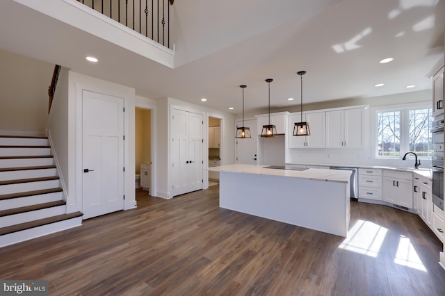 kitchen with pendant lighting, white cabinets, a center island, appliances with stainless steel finishes, and dark hardwood / wood-style floors