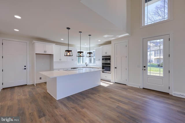 kitchen featuring pendant lighting, a center island, dark wood-type flooring, white cabinetry, and decorative backsplash