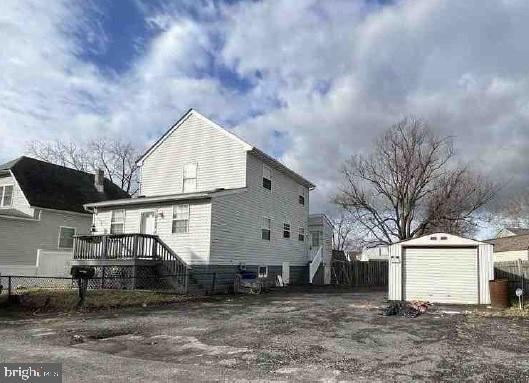 back of property with a deck, an outdoor structure, and a garage