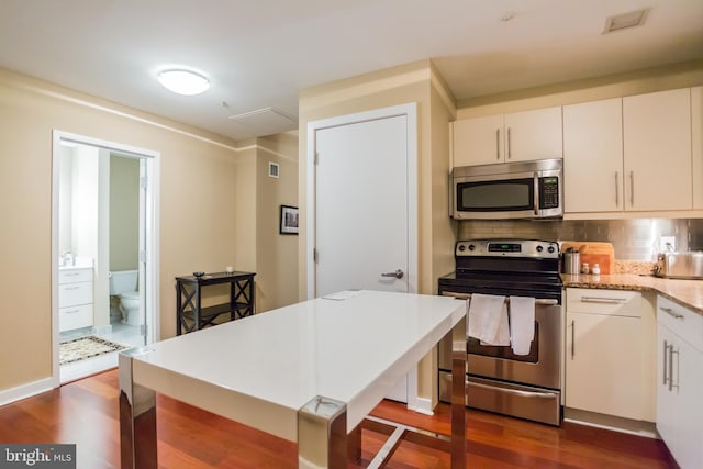 kitchen featuring appliances with stainless steel finishes, backsplash, white cabinetry, and dark hardwood / wood-style floors