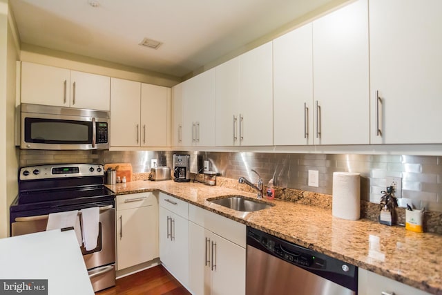 kitchen with white cabinetry, tasteful backsplash, appliances with stainless steel finishes, and sink