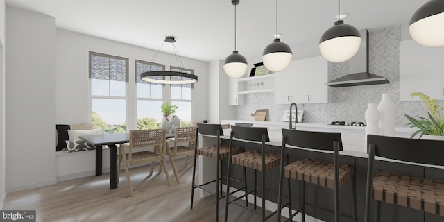 kitchen with white cabinetry, decorative light fixtures, decorative backsplash, and wall chimney range hood