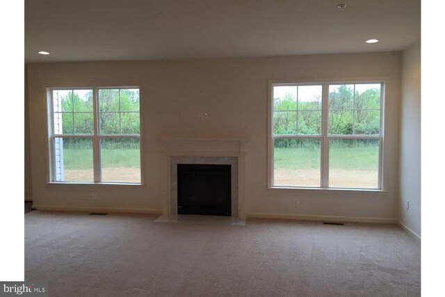 unfurnished living room with carpet flooring, baseboards, visible vents, and a premium fireplace