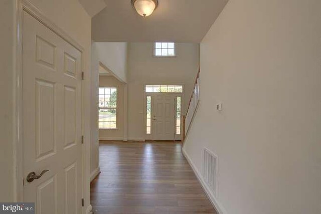 entrance foyer with wood finished floors, a healthy amount of sunlight, visible vents, and baseboards