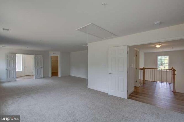 unfurnished room with carpet floors and attic access