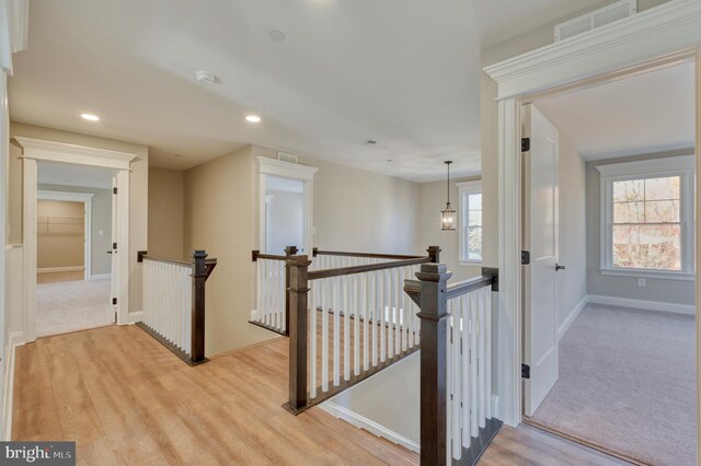 hallway featuring wood finished floors, recessed lighting, an upstairs landing, and visible vents