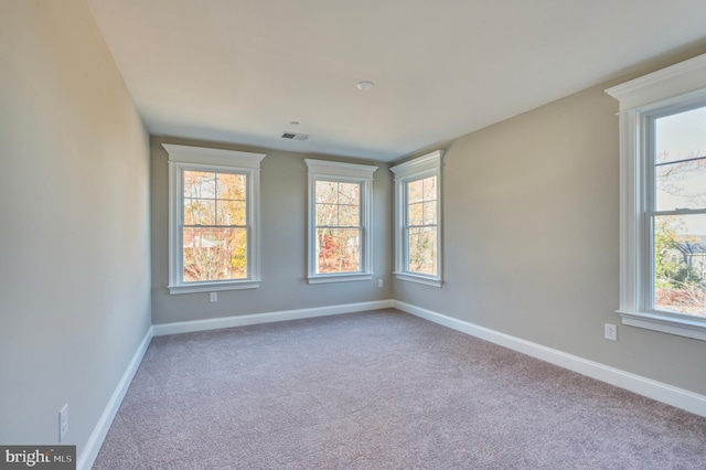 carpeted empty room featuring baseboards and a healthy amount of sunlight