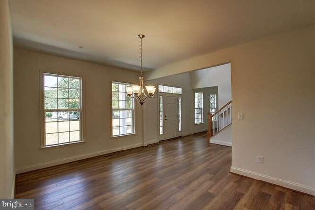 entrance foyer featuring stairway, an inviting chandelier, baseboards, and dark wood-style flooring