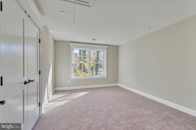 unfurnished bedroom with visible vents, baseboards, light colored carpet, attic access, and a closet