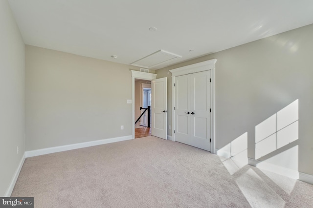 empty room with baseboards, attic access, and carpet flooring