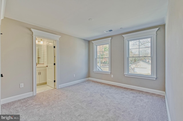 unfurnished bedroom featuring baseboards, visible vents, carpet floors, and connected bathroom