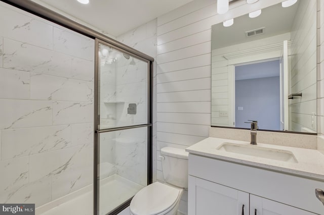 bathroom with visible vents, toilet, a marble finish shower, wooden walls, and vanity