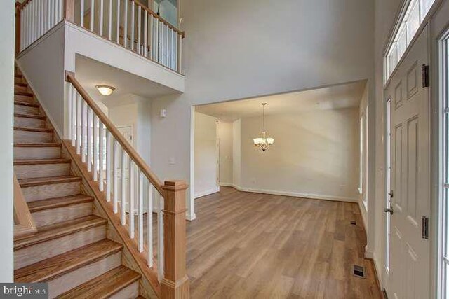 entrance foyer featuring wood finished floors, baseboards, visible vents, a high ceiling, and a chandelier