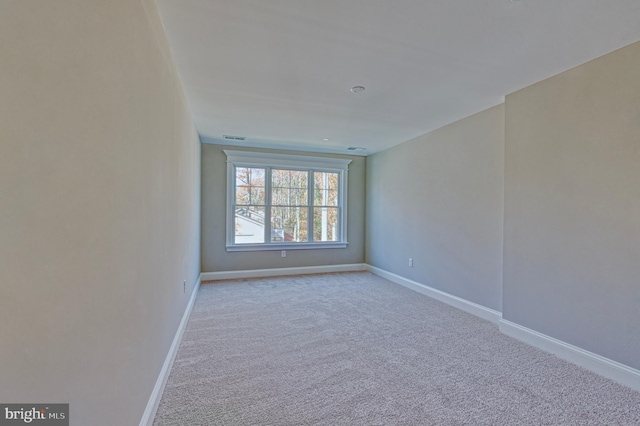 unfurnished room featuring visible vents, light colored carpet, and baseboards