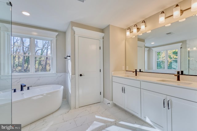 bathroom featuring a freestanding bath, visible vents, marble finish floor, and a sink