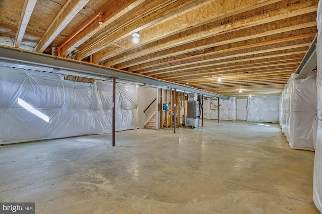 unfinished basement featuring heating unit and stairs