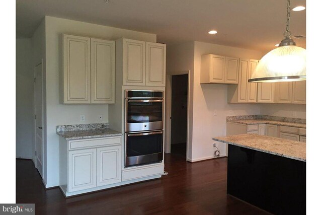 kitchen with light stone countertops, pendant lighting, recessed lighting, stainless steel double oven, and dark wood-style flooring