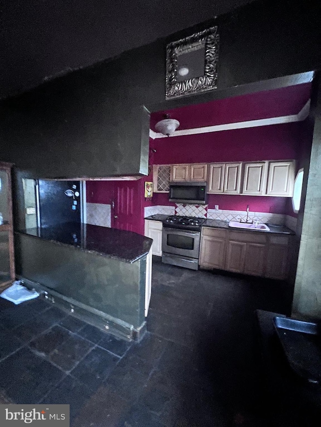 kitchen with backsplash, sink, dark stone countertops, and stainless steel appliances