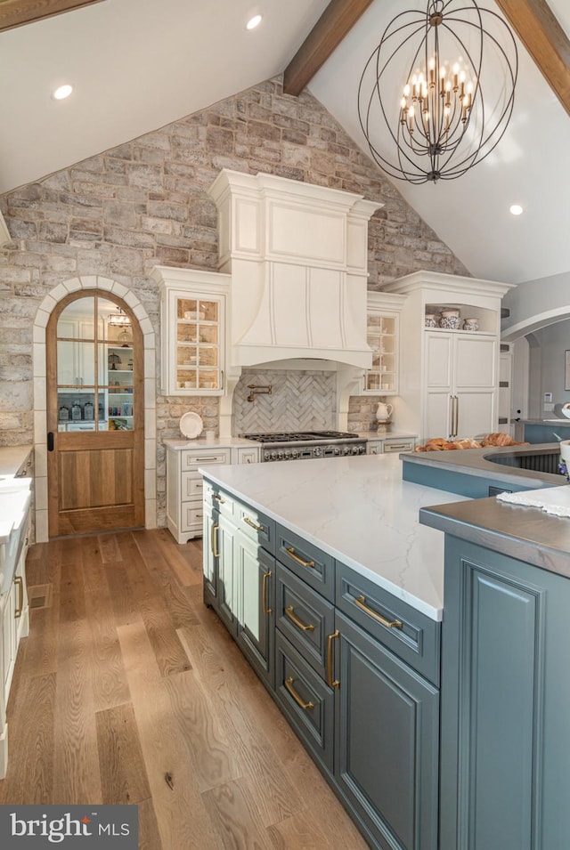 kitchen featuring light hardwood / wood-style flooring, lofted ceiling with beams, backsplash, white cabinets, and custom range hood