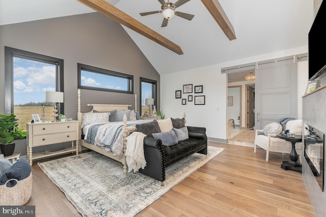 bedroom featuring ceiling fan, a barn door, high vaulted ceiling, beamed ceiling, and light hardwood / wood-style floors