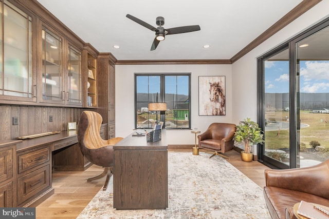 office area with built in desk, light hardwood / wood-style flooring, ceiling fan, and crown molding