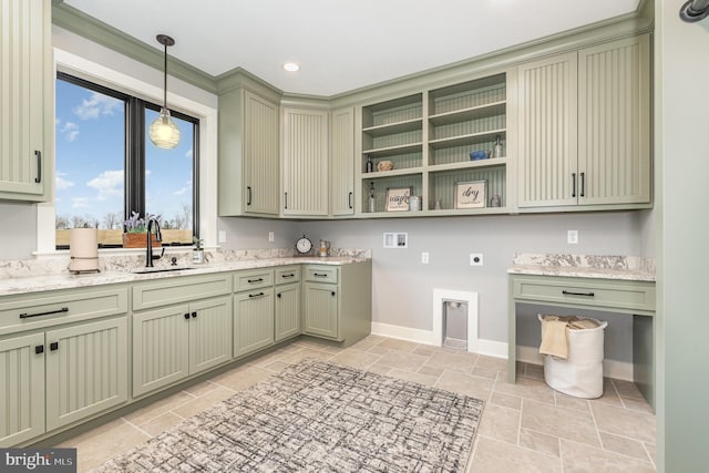 kitchen with light stone counters, sink, hanging light fixtures, and green cabinetry