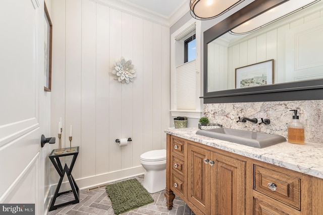 bathroom featuring toilet, vanity, and ornamental molding