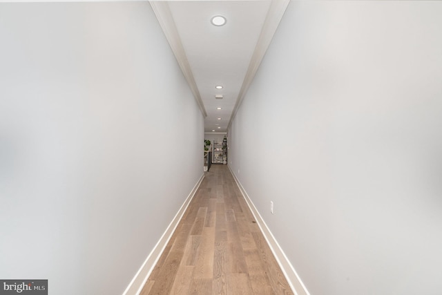 hallway with light wood-type flooring and ornamental molding