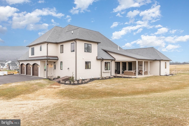 back of property with a lawn and a garage