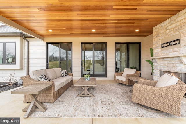 sunroom with an outdoor stone fireplace and wood ceiling