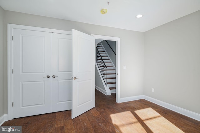 unfurnished bedroom with dark hardwood / wood-style floors and a closet