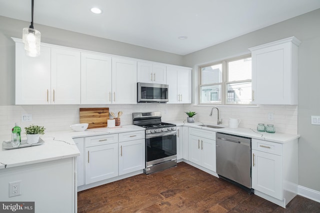 kitchen with hanging light fixtures, white cabinetry, sink, stainless steel appliances, and tasteful backsplash