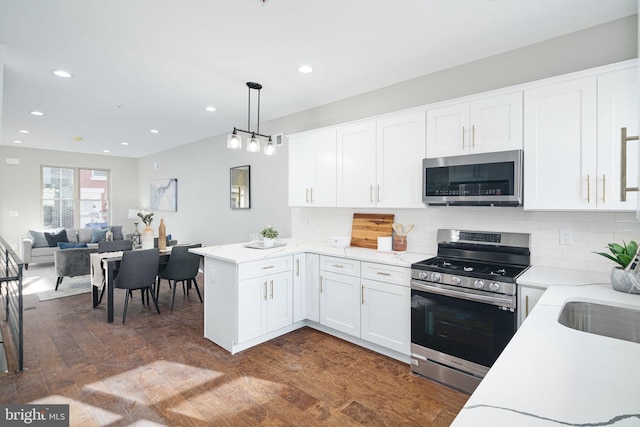 kitchen featuring pendant lighting, dark hardwood / wood-style flooring, appliances with stainless steel finishes, and white cabinetry