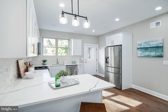 kitchen featuring wood-type flooring, stainless steel appliances, decorative light fixtures, sink, and white cabinetry