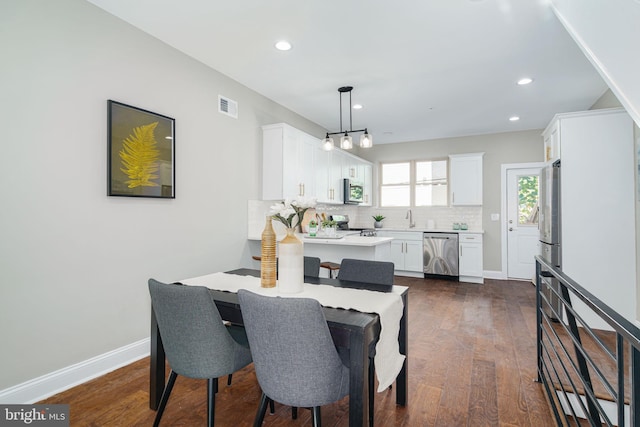 dining room with a notable chandelier, dark wood-type flooring, and sink