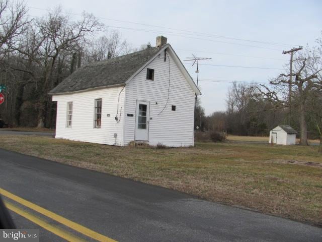 view of side of home with a lawn and a storage unit