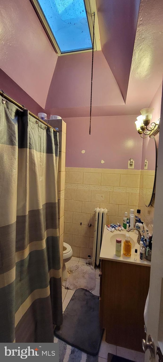 bathroom featuring vanity, tile walls, tile floors, toilet, and radiator