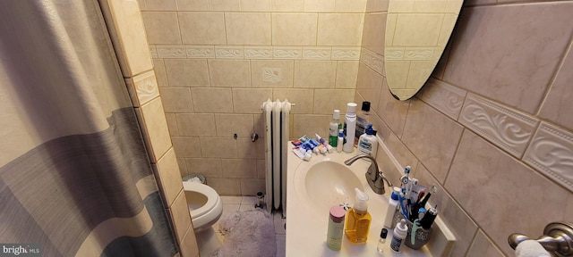 bathroom with tile walls, toilet, sink, tile flooring, and radiator heating unit